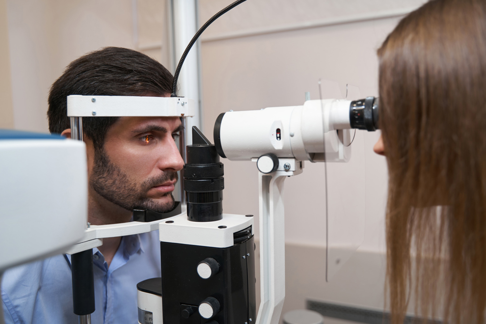 Optometrist testing eyes of patient