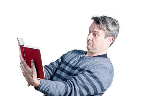 man struggling to read a book