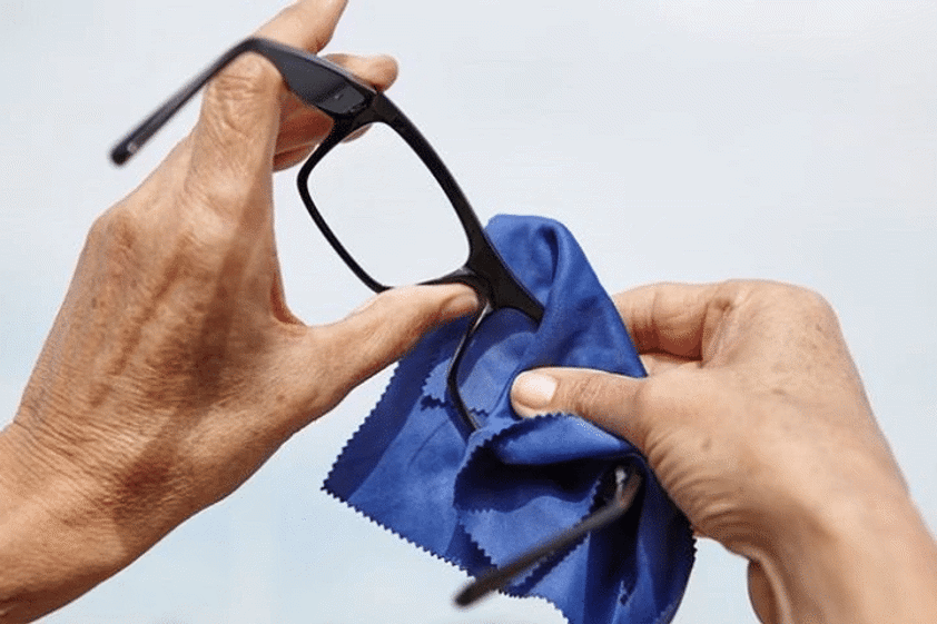 man cleaning his glasses